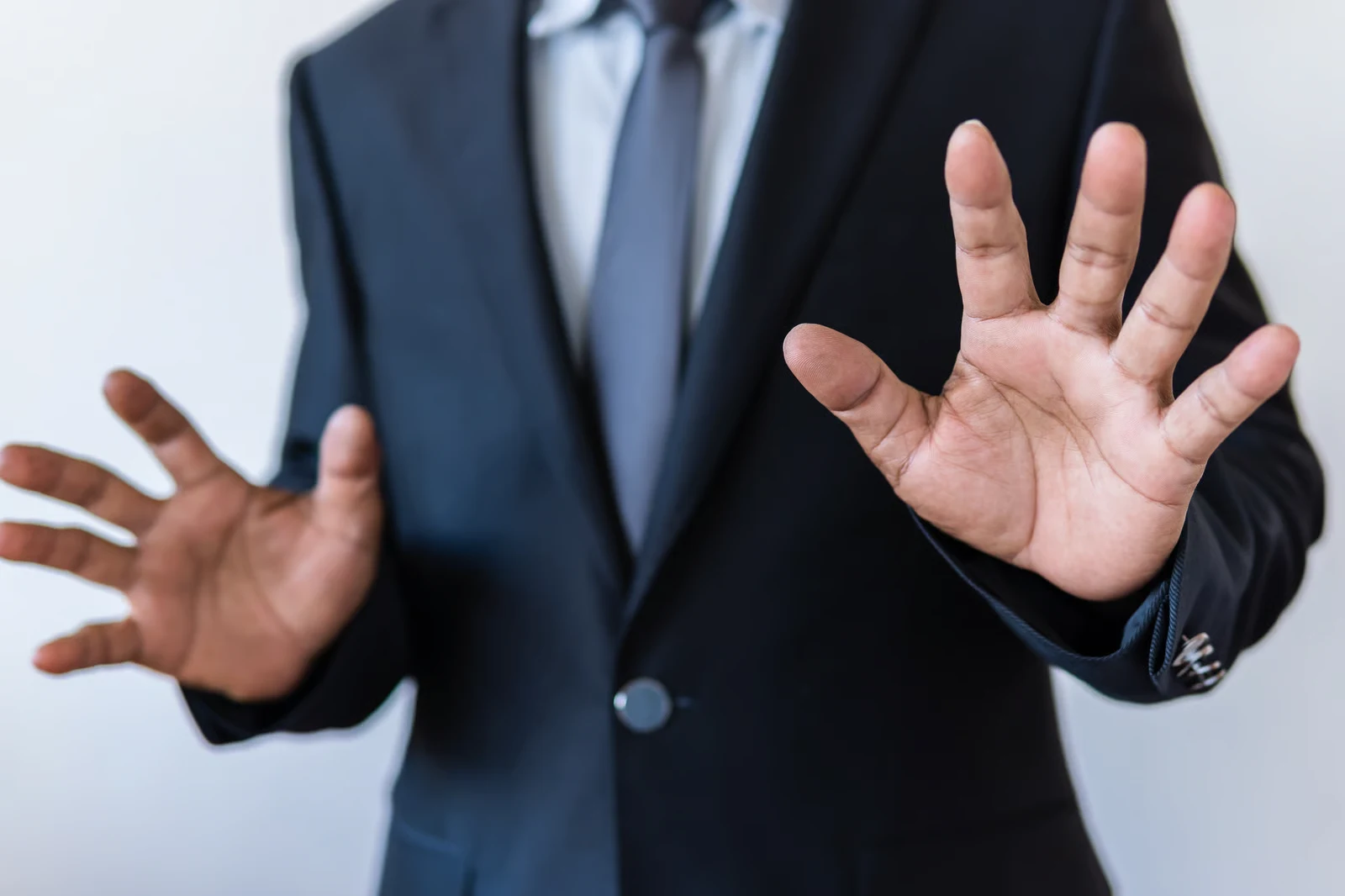 Homme en costume, mains levées en signe d arrêt — les limites d une politique de prévention du harcèlement.